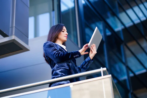 Femme d'affaires portant un costume bleu en utilisant une tablette numérique dans un immeuble de bureaux. — Photo