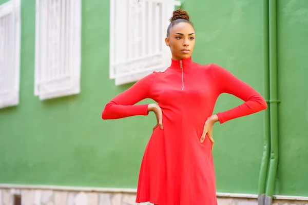 Giovane donna nera in abito rosso di fronte a un muro verde — Foto Stock