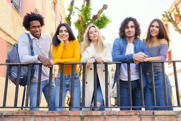 Gruppo multietnico di amici riuniti in strada appoggiati a una ringhiera. — Foto Stock