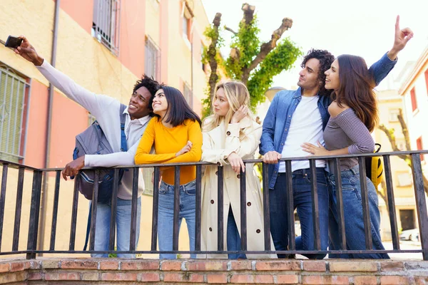 Grupo multi-étnico de amigos tirando uma selfie na rua com um smartphone. — Fotografia de Stock