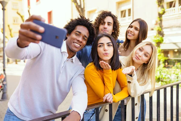 Multi-etnische groep van vrienden nemen van een selfie buiten met een smartphone. — Stockfoto