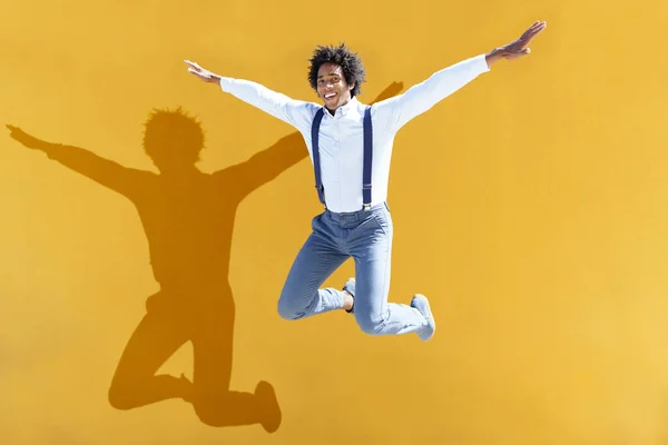 Schwarzer Mann mit Afrohaaren springt auf gelbem urbanen Hintergrund — Stockfoto