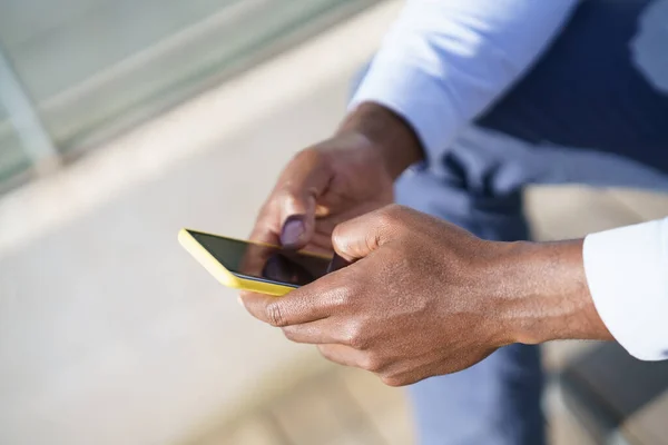Manos de hombre negro irreconocible usando un teléfono inteligente. —  Fotos de Stock