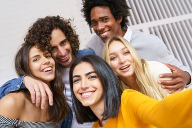 Çok ırklı bir grup arkadaş dışarıda eğlenirken selfie çekiyorlar..