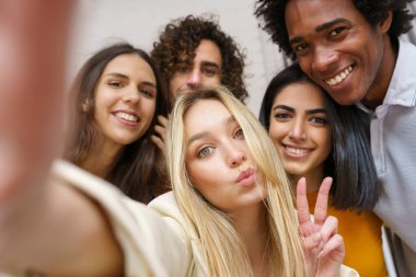 Çok ırklı bir grup arkadaş dışarıda eğlenirken selfie çekiyorlar..