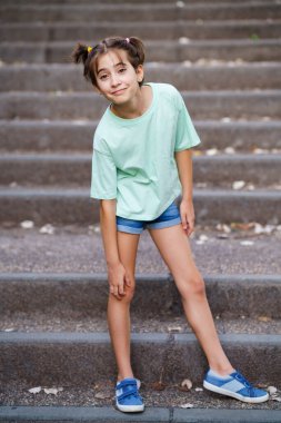 9 yaşında bir kız merdivenlerde dikiliyor.