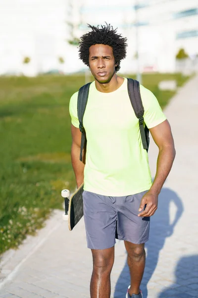 Schwarzer Mann beim Workout in Sportbekleidung und Skateboard. — Stockfoto