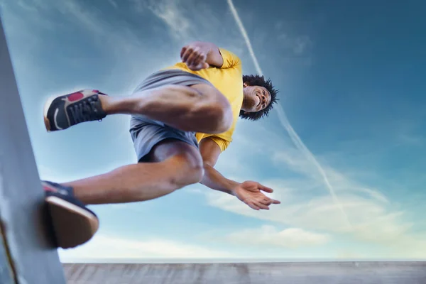 Вид снизу на чернокожего человека, прыгающего во время пробежки. — стоковое фото