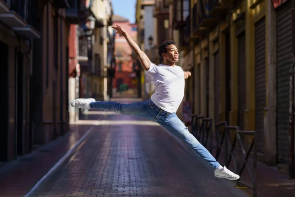 Black athletic man doing an acrobatic jump outdoors — Stock Photo, Image