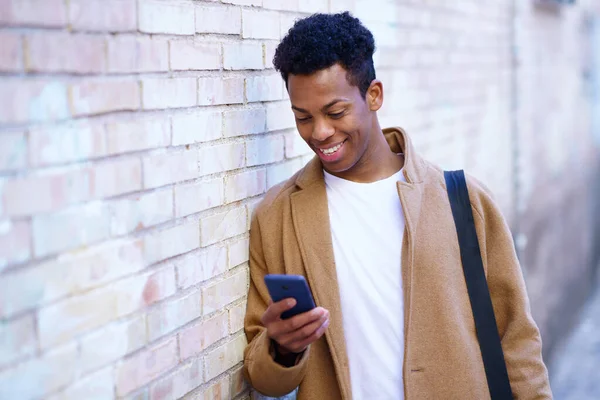 Giovane cubano utilizzando uno smartphone vicino a un muro urbano. — Foto Stock