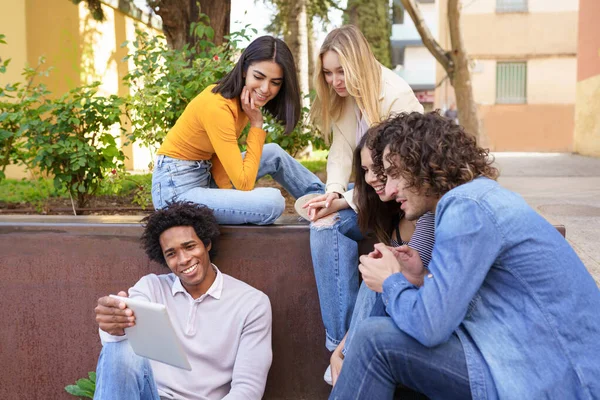 Gruppo multietnico di giovani che guardano un tablet digitale all'aperto su sfondo urbano. — Foto Stock
