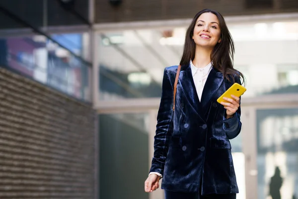 Donna d'affari che indossa un abito blu utilizzando lo smartphone in un edificio per uffici. — Foto Stock