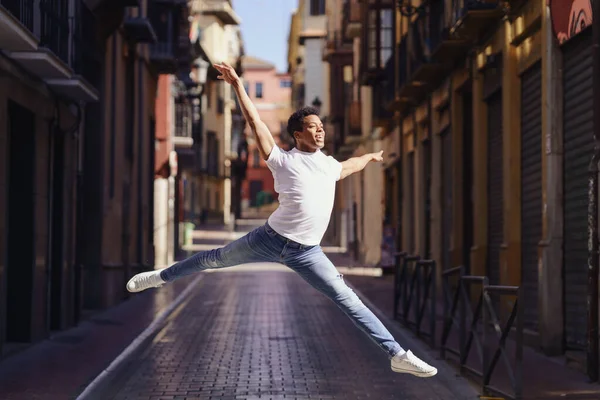 Happy black guy doing an acrobatic jump in the middle of the street. — Stock Photo, Image