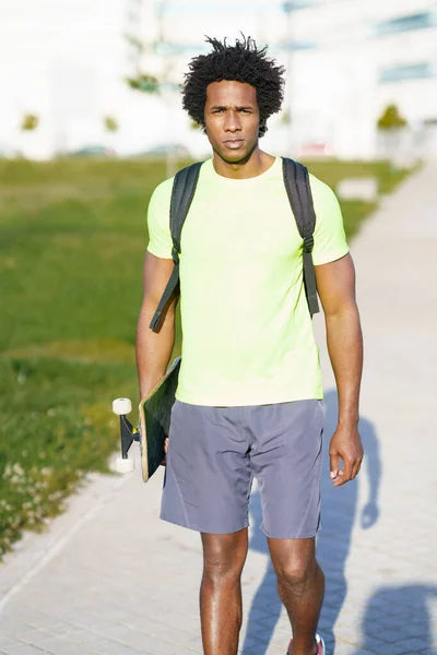 Schwarzer Mann beim Workout in Sportbekleidung und Skateboard. — Stockfoto