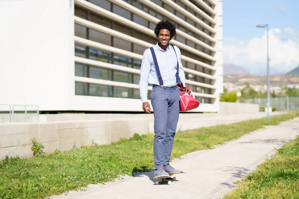 Μαύρος επιχειρηματίας ιππασία skateboard κοντά στο κτίριο γραφείων. — Φωτογραφία Αρχείου