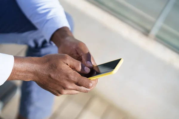 Händerna på oigenkännlig svart man med hjälp av en smartphone. — Stockfoto