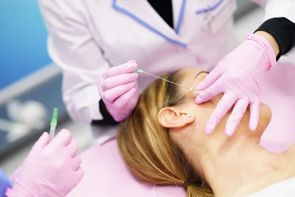 Arzt spritzt einer Frau Fäden einer PDO-Nahtbehandlung ins Gesicht. — Stockfoto