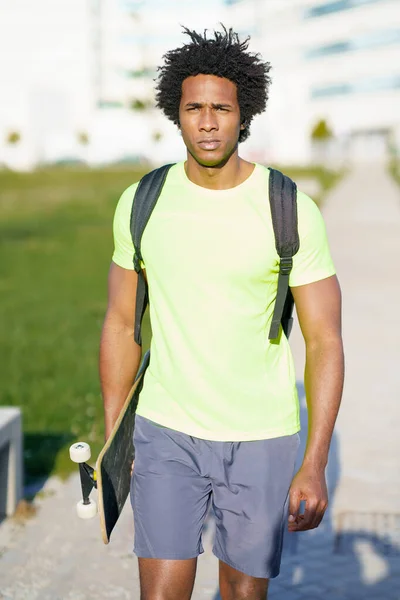 Schwarzer Mann beim Workout in Sportbekleidung und Skateboard. — Stockfoto