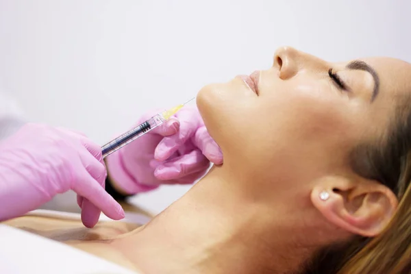 Az orvos arcfiatalító kezelésként hialuronsavat fecskendez egy nő bőrébe. — Stock Fotó