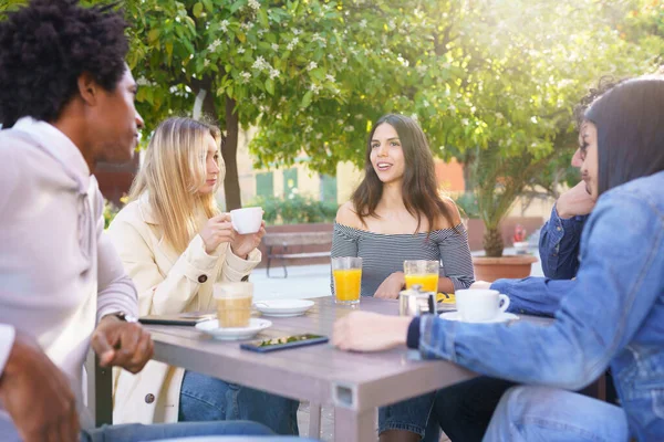 Grupo multiétnico de estudiantes tomando una copa en la terraza de un bar de la calle. — Foto de Stock