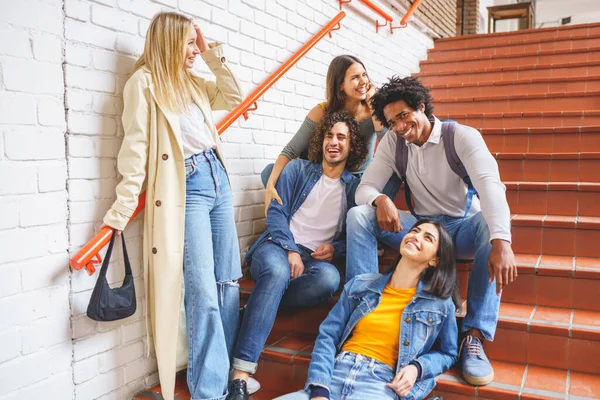 Grupo de amigos con variedad étnica, sentados en algunos escalones de la calle divirtiéndose juntos. —  Fotos de Stock