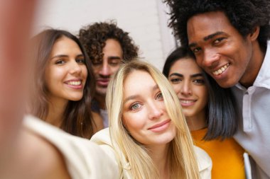 Çok ırklı bir grup arkadaş dışarıda eğlenirken selfie çekiyorlar..