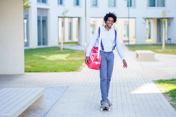 Černý podnikatel jízda na skateboardu v blízkosti administrativní budovy. — Stock fotografie