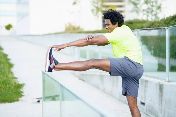 Schwarzer Mann mit Afro-Haaren beim Stretching nach dem Laufen im Freien. — Stockfoto