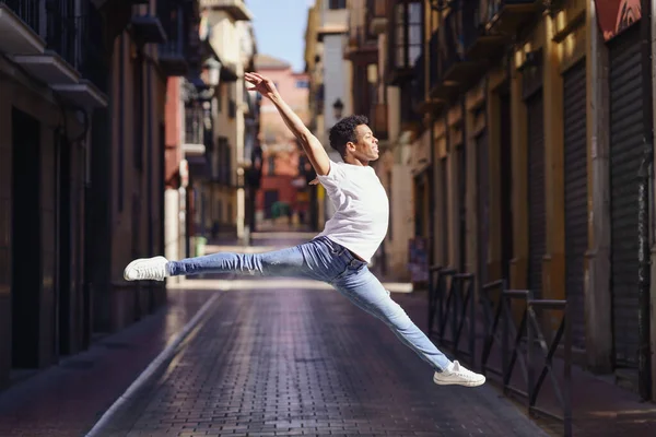Junger schwarzer Mann macht einen akrobatischen Sprung mitten auf der Straße. — Stockfoto