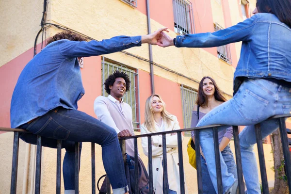 Grupo multiétnico de amigos reunidos na rua apoiados em um corrimão. — Fotografia de Stock