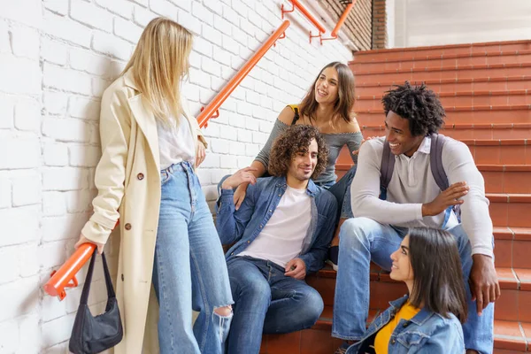 Grupo de amigos con variedad étnica, sentados en algunos escalones de la calle divirtiéndose juntos. — Foto de Stock