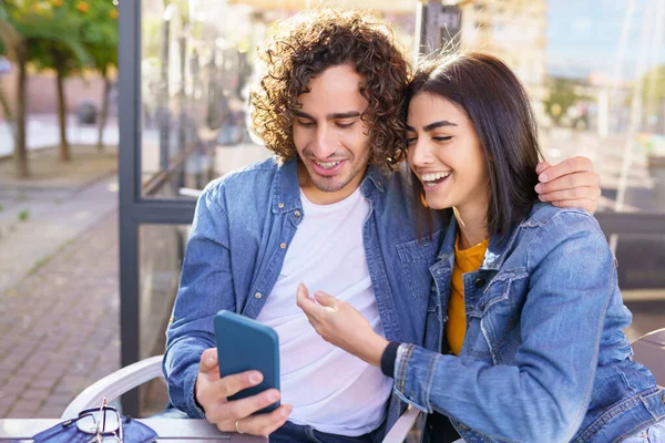 Arap çift dışarıda akıllı telefonlarıyla çekilmiş fotoğraflara bakıyor. — Stok fotoğraf