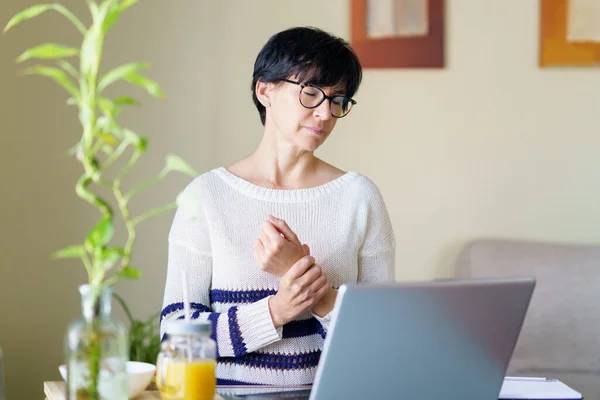 Woman teleworking from home with wrist pain having a massage to rest. — Stockfoto