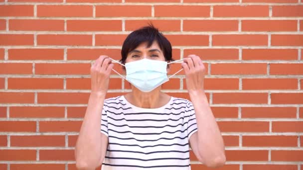 Middle-aged woman removing covid-19 mask, end of pandemic. Caucasian person. Slow motion video. — Stockvideo