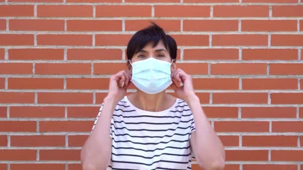 Middle-aged woman removing covid-19 mask, end of pandemic. Caucasian person. — Stockvideo