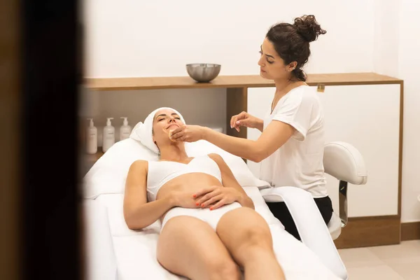 Estética limpando a pele para o rosto de uma mulher de meia-idade no centro de bem-estar moderno. — Fotografia de Stock