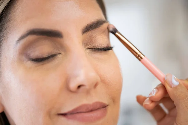 Primer plano de una maquilladora que aplica sombra de ojos a su cliente. — Foto de Stock