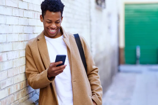 Giovane uomo nero utilizzando il suo smartphone all'aperto. — Foto Stock