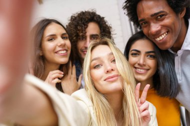 Çok ırklı bir grup arkadaş dışarıda eğlenirken selfie çekiyorlar..