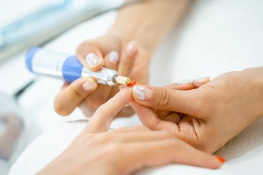 Manikürcüde bir kadın manikür yaptırıyor..