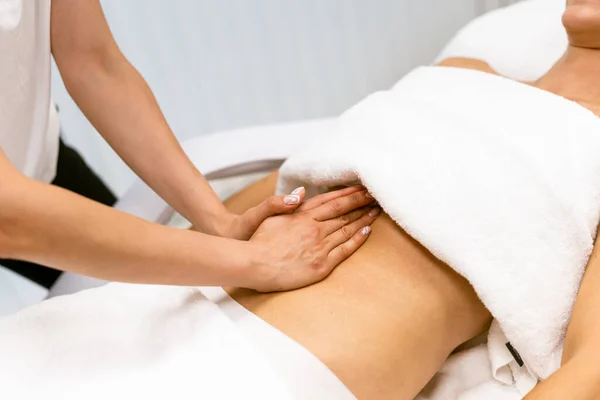 Middle-aged woman having a belly massage in a beauty salon. — Stock Photo, Image