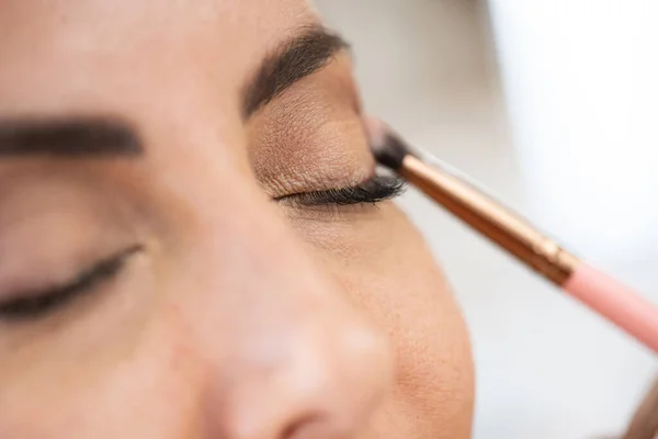 Close-up van een make-up kunstenaar die oogschaduw op haar cliënt aanbrengt. — Stockfoto