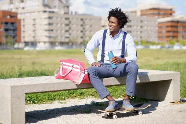 Uomo nero con i capelli afro prendendo una pausa caffè seduto su una panchina del parco. — Foto Stock