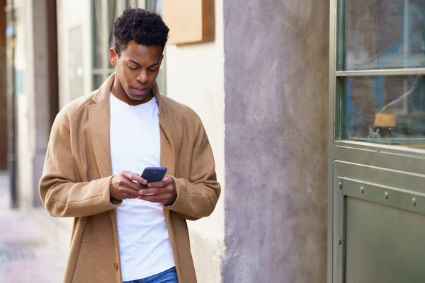 年轻的黑人男子在户外用智能手机. — 图库照片