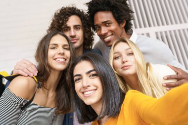 Çok ırklı bir grup arkadaş dışarıda eğlenirken selfie çekiyorlar..