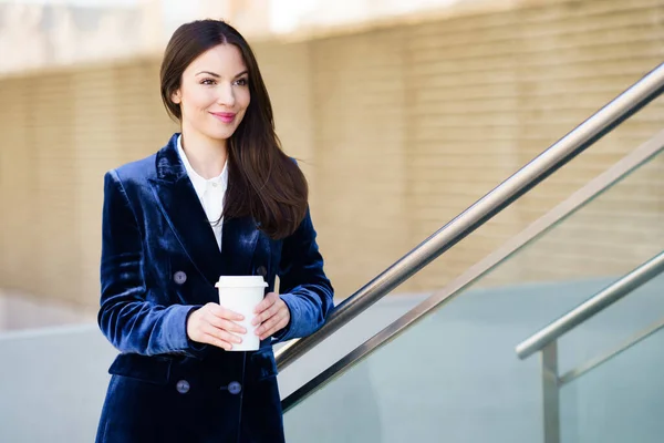 Affärskvinna i blå kostym tar en kaffepaus utanför sitt kontor. — Stockfoto