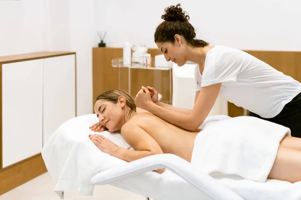 Masajista femenina dando un masaje de espalda a una mujer en un salón de belleza. — Foto de Stock