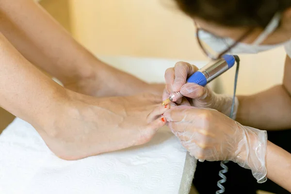 Esteticista dando una pedicura pintando las uñas de sus clientes en un centro de belleza. —  Fotos de Stock