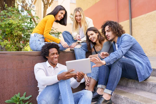Gruppo multietnico di giovani che guardano un tablet digitale all'aperto su sfondo urbano. — Foto Stock