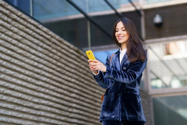 Donna d'affari che indossa un abito blu utilizzando lo smartphone in un edificio per uffici. — Foto Stock